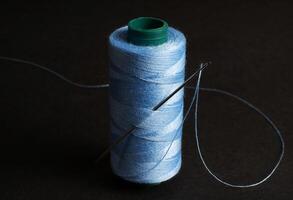 blue thread spool with needle isolated photo