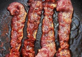 Bacon slice being cooked in frying pan photo