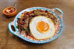 Stir fried beef with basil and dried chili paste over white rice with Thai fried egg on wooden background. photo