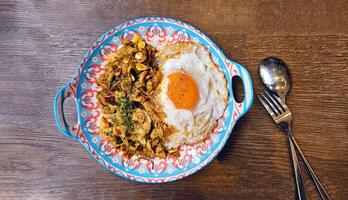 Top view of Stir fried beef, pork or chicken with southern yellow curry paste over rice with Thai fried egg and spoon with fork on wooden background. photo
