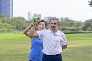 senior man doing exercise with dumbbell with trainer,elderly having physical activity in the park photo