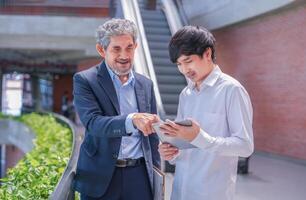 senior professor giving advice student in campus building,a young man holding tablet computer consult instructor the research study,concept back to school and education photo