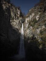 Powerful waterfall cascading down rugged cliffs in aosta, italy, surrounded by natural rock formations and bathed in soft november light Isollaz waterfall photo