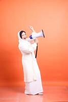 Enthusiastic muslim female, shouting into a megaphone with expre photo