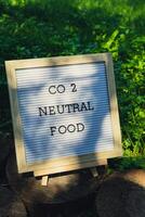 Letter board with text CO2 NEUTRAL FOOD on background of garden bed with green herb parsley. Organic farming, produce local vegetables concept. Supporting local farmers. Seasonal market photo