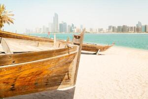 Abu Dhabi skyline with old traditional fishing boats in Heritage Village in Abu Dhabi in United Arab Emirates UAE. Couple tourist enjoy beach and visit sightseeing travel destination in UAE photo