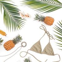 Vacation concept - pineapples, cosmetic with bikini on white. Flat lay, top view. photo