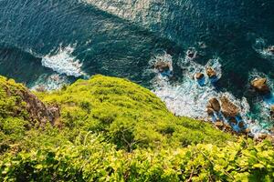Ocean with waves crashing on rocks stones, view from high rocky coastline photo