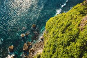 Ocean with waves crashing on stones, view from cliff coastline photo