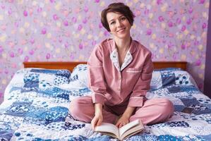 Portrait Happy woman wears pajama and relaxing at home and reading a book. photo
