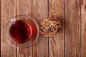 A cup of tea and a biscuit on a wooden table photo