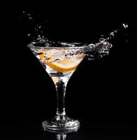 A martini glass with a slice of lemon and water splashing photo