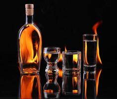 A bottle of alcohol and two glasses with flames photo