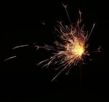 A sparkler is lit on a black background photo
