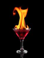 A red liquid in a martini glass with flames coming out of it photo