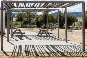 Two Empty gray wooden tables on the green plants background with a pergola photo