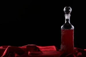 A bottle of red liquid sitting on a red cloth photo