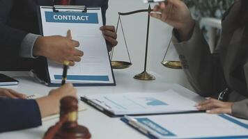 A group of people are sitting at a table with a contract video