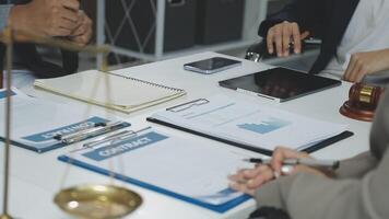 un grupo de personas sentado a un mesa con documentos y un escala video