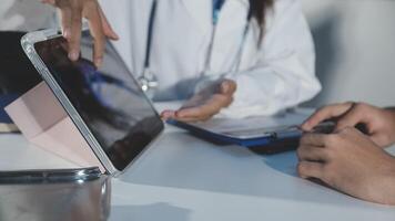 A doctor is holding a tablet computer while a patient is looking at it video
