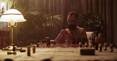 Perfumer in glasses mixing oils while creating handmade perfume video