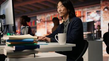 Senior engineer coding AI algorithm in startup office, refining machine learning models to enhance automation. Asian CTO manager using coding platform in Silicon Valley workplace, camera A photo