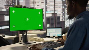 administrator focused on financial planning next to chroma key screen, reviewing infographics for data analysis and company strategy. Businessman ensuring enterprise solutions. Camera B. photo