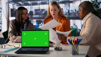Multiethnic businesswomen working next to isolated green screen, solving daily tasks for project to achieve enterprise objectives and work on global development. Corporate feminism. Camera B. photo