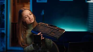 Gen Z girl presenting RGB lit mouse and keyboard, doing review in personal studio to see if price is justified. Young influencer showcasing neon lit computer peripheral features to fans, camera A photo