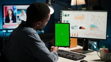 Young guy examining funds for program, holding tablet with mockup, studying finances and accounting management on software. Male specialist doing remote work for startup. Camera B. photo