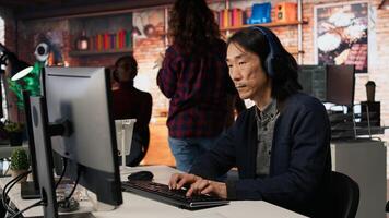 Chief technology officer listens to music and codes application in startup office. Senior programmer wearing headphones while working in artificial intelligence software development agency, camera A photo
