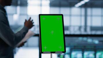 Isolated screen tablet in front of technicians working in server farm, analyzing data. Close up of chroma key device next to coworkers examining data center, camera A photo