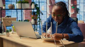 African american woman restarting wireless router and checking network settings to resolve internet error disrupting daily tasks. Frustration due to signal loss. Camera A. photo