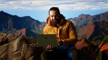 Nature lover workaholic always connected to internet and scrolling on laptop, enjoying strong signal on mountain top with breathtaking landscape. Uninterrupted work. Camera B. photo