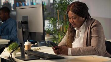African american manager taking break from business work and browsing social media, checking messages and websites at desk. Analyst multitasking and texting during schedule. Camera A. photo