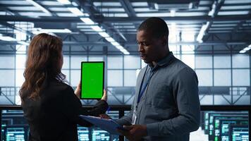 Technicians using green screen tablet, reviewing hardware diagnostics. IT coworkers adjusting server configurations using mockup device, applying firmware updates, camera B photo