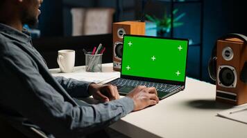 Teleworker editing documents next to mockup display on laptop, submitting reports and files before deadline. Black freelancer managing digital paperwork within work platform. Camera B. photo
