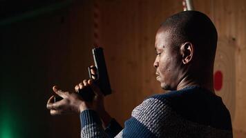Shooting range customer reloading pistol, preparing to shoot targets during recreational sport activity. Man at firing range loading pistol with ammunition, camera A close up photo