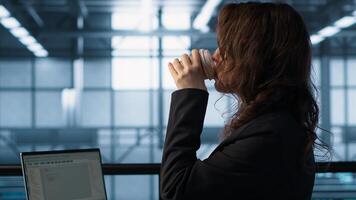Technician using laptop in data center, finetuning network protocols and holding coffee cup. Woman in server room coding on notebook, enforcing advanced security measures, camera A photo
