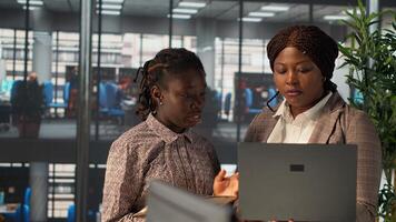 Professional women analyzing archived data on modern device, collaborating on enterprise solutions and financial planning tasks to improve company performance for long term growth. Camera A. photo