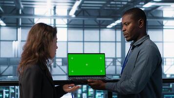 Technicians in data center using green screen laptop to develop disaster recovery plans. IT specialists in server farm testing failover scenarios on chroma key device, protecting data, camera A photo