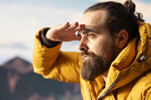 Hiker gazes at panoramic view of dramatic mountain peaks and clouds, feeling thrill of adventure and rewards of perseverance. The journey represents strength and personal growth. photo