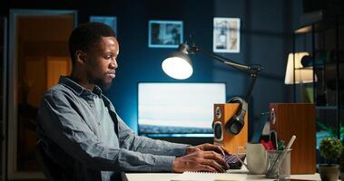 Exhausted black developer trying to meet task deadline, working hard to finish report in time and dealing with headache. African american guy being under stress with pressure. Camera A. photo