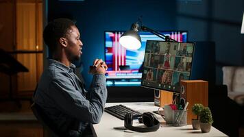 Black man meeting with group of individuals on web conference, using technology for virtual communication. Freelancer working remotely, online meetings or classes in cozy home. Camera B. photo