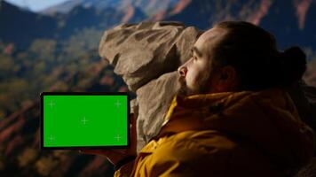 Happy adventurer standing at rocky top next to copy space display, feeling power of accomplishment. Man examines mountain range, peaceful sky and vast wilderness. Camera B. photo
