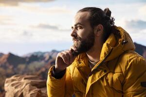 Determined traveler enjoys solitude of mountain summit, where panoramic view represents adventure and personal growth. Hiker with outdoor gear feeling cold on windy mountain top. photo