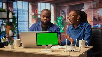 African American couple browse troubleshooting guide next to chroma key, working together to debug router issues and restore home network. Freelancers getting angry. Camera A. photo