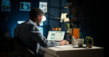 African American teleworker managing daily schedule and does post it memo notes, creating reminder to ensure task completion from home office. Freelancer improving productivity. Camera A. photo