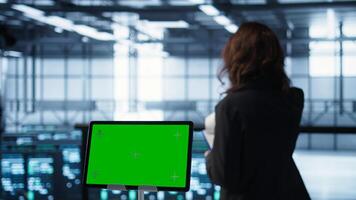 Close up of chroma key tablet and programmers in server room adjusting power management settings. Focus on isolated screen mockup device in front of data center technicians, camera B photo