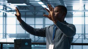 Computer scientist looking at holograms in data center, using artificial intelligence. African american admin interacting with augmented reality visualization in server room, camera A photo